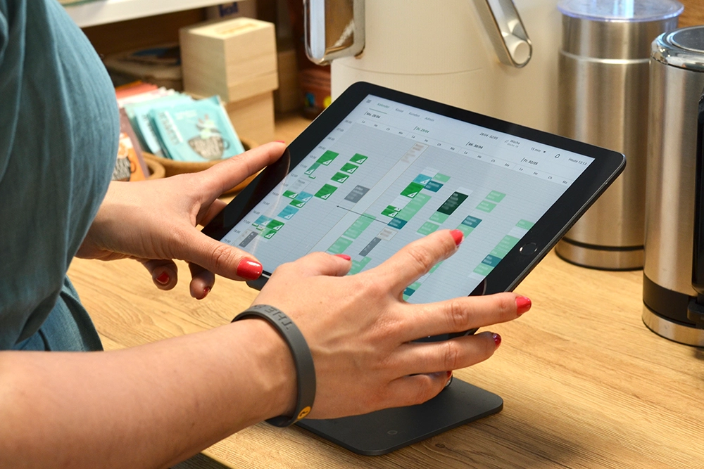 Digitale Tools Die Hände einer Mitarbeiterin bedienen ein Tablet, au dem die Terminorganisation verwaltet werden kann.