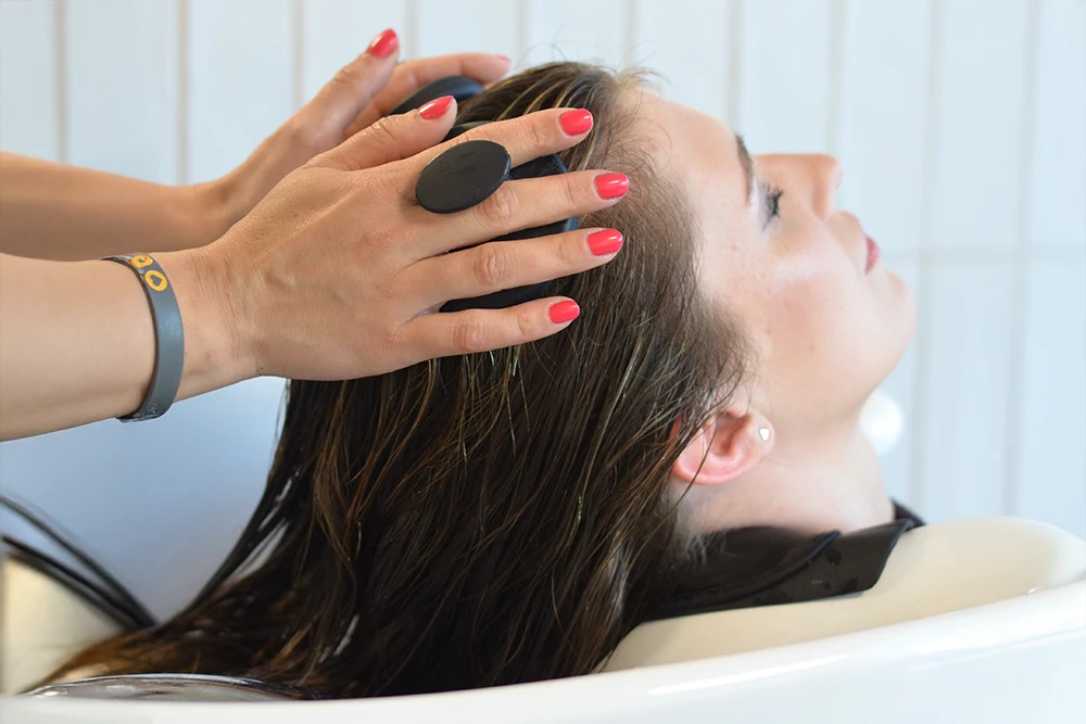 Kopfmassage Eine Kundin bekommt nach dem Haarewaschen eine Kopfmassage und fühlt sich sichtlich wohl.